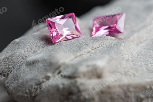 Preview: Glimmering natural pink sapphire gemstones on a rugged rock surface