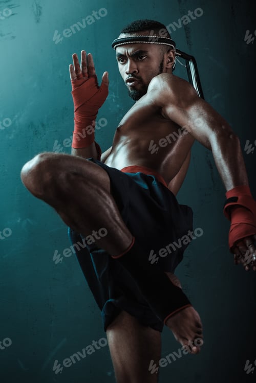 Preview: Low angle view of determined Muay thai fighter training thai boxing, ultimate fight concept