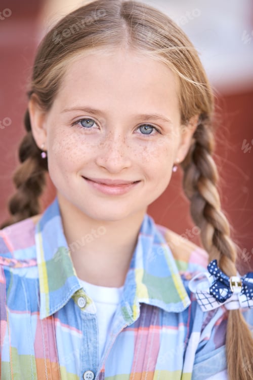 Preview: Smiling caucasian female child with braided hair in colorful checkered shirt