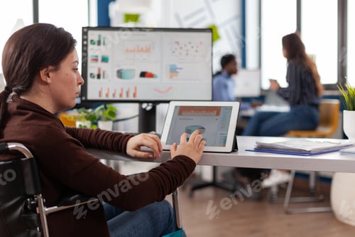Preview: Paralyzed businesswoman analyzing financial digitat graphs on tablet