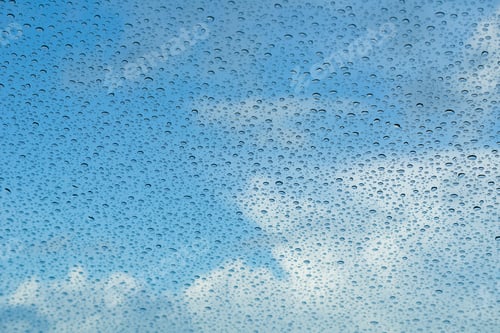 Preview: Raindrops on the windshield; in the background blue sky and white clouds, California