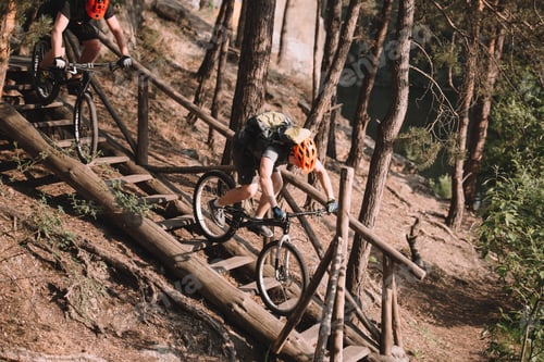 Preview: young trial bikers riding down stairs in forest