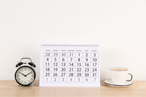 Preview: Calendar, alarm clock and cup of coffee on wooden table