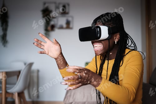 Preview: Cheerful black woman with vitiligo skin playing videogame in VR