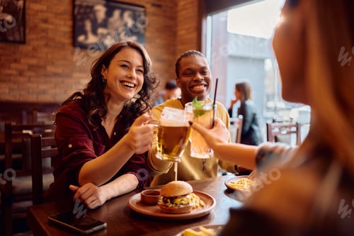 Preview: Happy woman having fun while toasting with her friends in a bar.