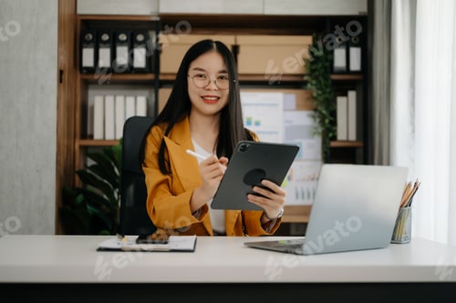 Preview: Asian businesswoman working in the office with working notepad, tablet and laptop