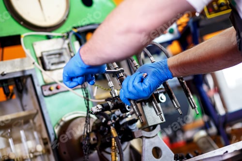 Preview: Professional mechanic testing diesel injector in his workshop.