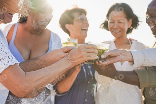 Preview: Senior friends cheering with mojito on the beach during travel vacation