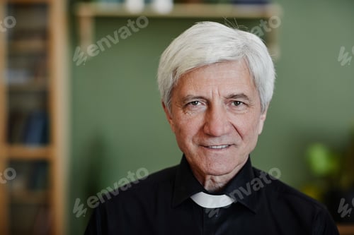 Preview: Close up white haired senior priest smiling at camera in office setting