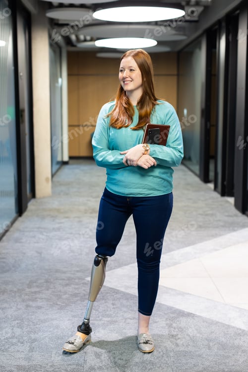 Preview: Walking in office, woman with prosthetic leg holding tablet and smiling
