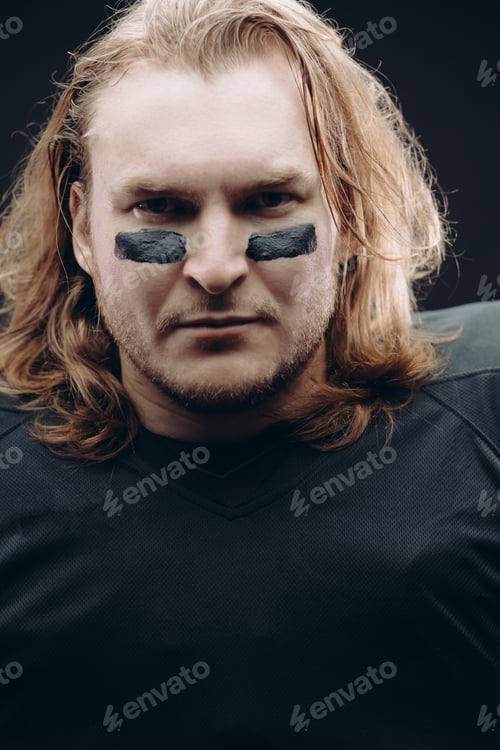 Preview: Determined American football player posing with painted face and chewing gum