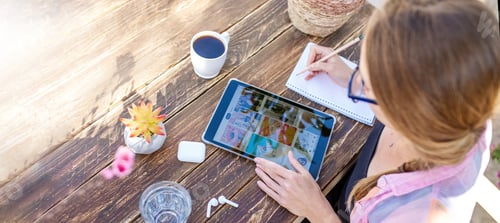 Vista previa: Jovencita en busca de inspiración en la aplicación de Pinterest y escribiendo notas