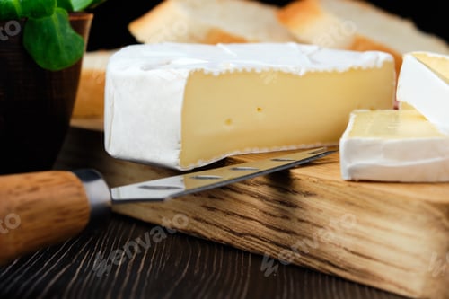 Preview: Close up of camembert or brie cheese on wooden cutting board