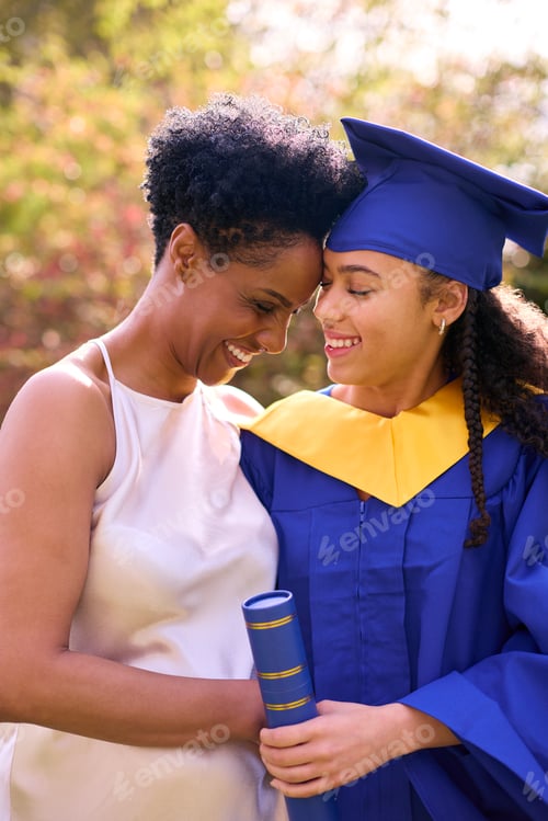 Preview: Proud Mother Celebrating With Teenage Daughter Wearing Graduation Robes Outdoors