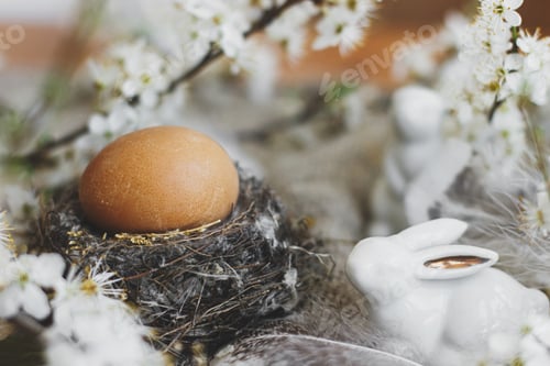 Preview: Natural Easter egg in nest,white bunnies, feathers and cherry blooming flowers on rustic linen