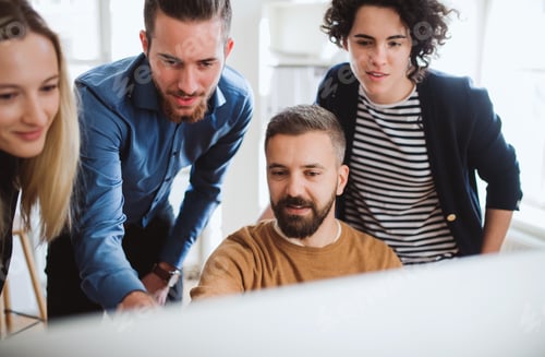 Preview: Group of young businesspeople looking at laptop screen in office, discussing issues.
