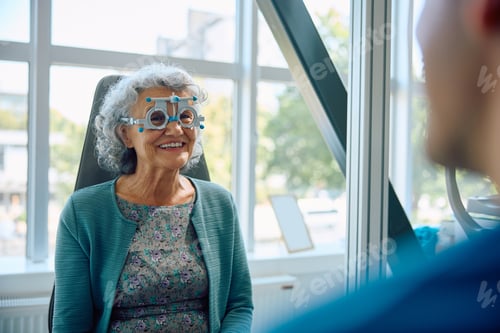 Preview: Happy elderly woman with optical testing glasses during eyesight exam at ophthalmologist.