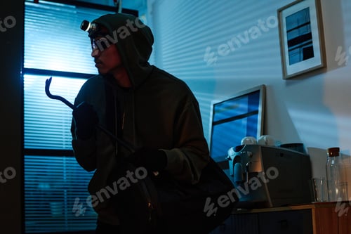 Preview: Young Adult Man Stealing Office Equipment during Nighttime Break in