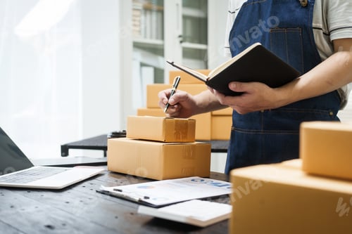Preview: A man is working at his desk, preparing parcel boxes for shipment. He checks packs items carefully