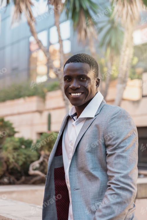 Preview: Cheerful young African American male entrepreneur in classy jacket and white shirt looking at
