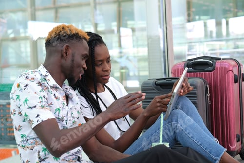 Preview: Young black couple checking their travel information on a tablet.