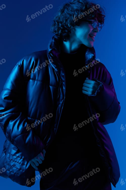 Preview: Man in winter down jacket model posing with glasses, hipster lifestyle, portrait blue background