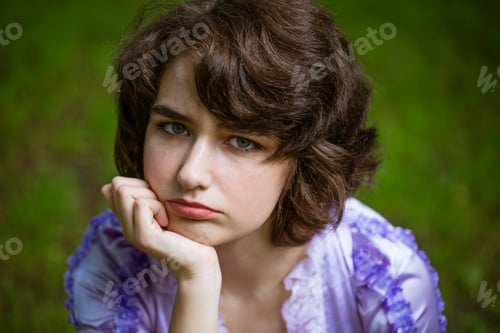 Preview: Rubs young sad woman on natural background. Cute girl looks