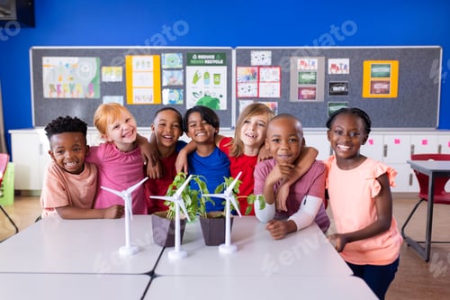 Preview: In school, group of diverse children smiling around table with wind turbines