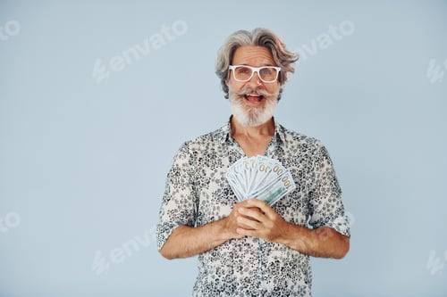 Preview: Millionaire with cash in hands. Senior stylish modern man with grey hair and beard indoors
