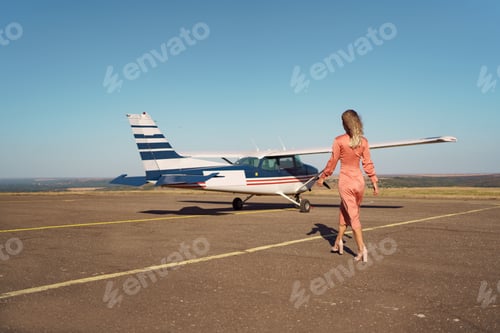 Preview: Stylish Woman Walking toward Airplane on Runway
