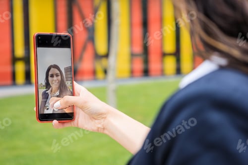Preview: Businesswoman taking selfie in the park. Close-up of the screen.