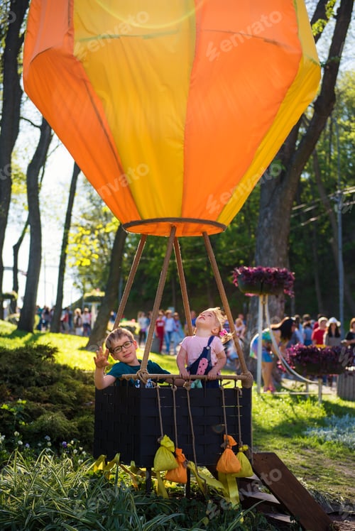 Preview: Siblings in the orange balloon imitating flight in the sky.