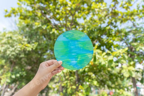 Preview: Hand holding earth sign up with natural environment sky and tree as background