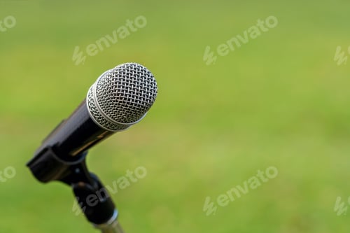 Preview: Microphone on the stage over the Abstract blurred photo of green grass with bokeh of light
