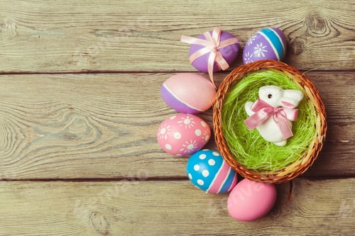 Preview: Cute bunny and colorful eggs in basket on wooden table during Easter celebration