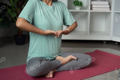 Preview: Senior woman practicing mindful breathing on a yoga mat in a tranquil indoor setting