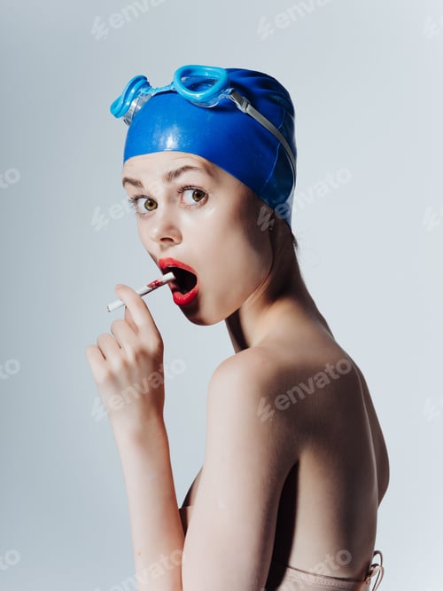Preview: athletic woman in swimming goggles smokes a cigarette isolated background