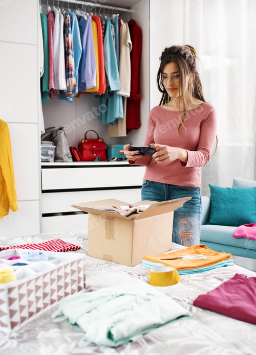 Preview: Woman taking pictures of clothes in a box