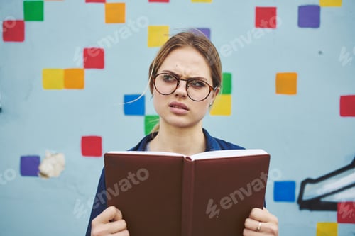 Preview: Surprised female student in glasses on the street with a book of emotions model