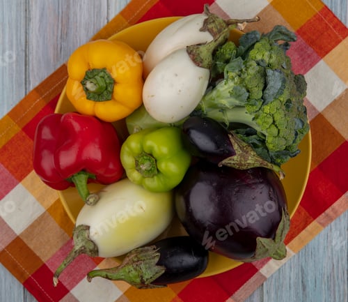 Preview: top view of vegetables as pepper broccoli and eggplant in plate on plaid cloth on wooden background