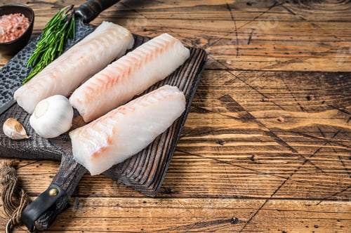 Preview: Fresh Raw cod loin fillet steaks on wooden board with butcher knife. wooden background