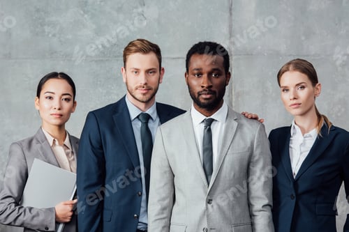 Preview: serious multiethnic group of businesspeople in formal wear posing and looking at camera