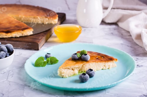 Preview: Appetizing thin cheesecake with honey and blueberries on a plate on the table. Homemade pastries