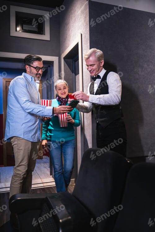 Preview: Senior couple scanning tickets at movie theater with usher assisting