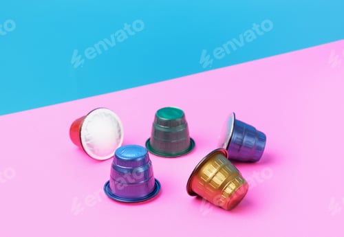 Preview: Multi-colored capsules for coffee machine close-up on pink and blue background.