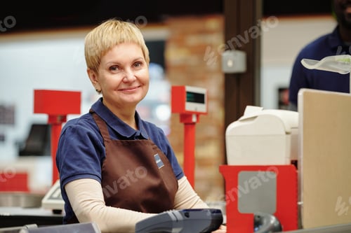 Preview: Successful mature clerk in uniform sitting by checkout counter