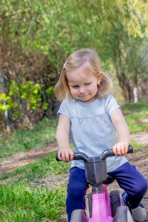 Preview: Little girl riding a balance bike. nature.