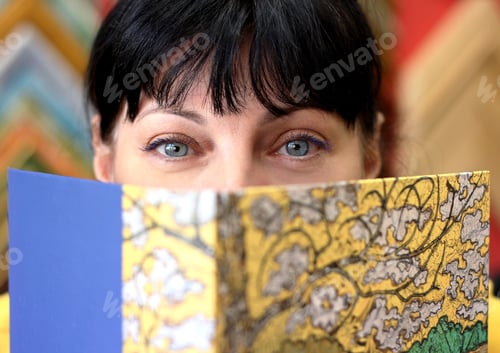 Preview: A woman looking in the camera over a book cover