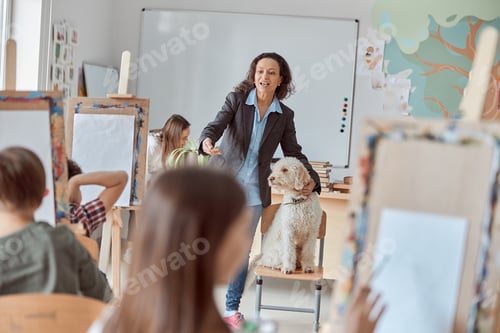 Preview: Creative female african mixed raced teacher shows a dog to drawing kids on a group lesson at school