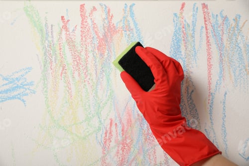 Preview: Woman erasing child's drawing from white wall, closeup